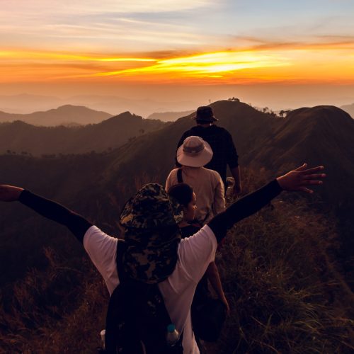 Rear view of four backpacker walking in path on mountain at sunset Rear view of four backpacker walking in path on mountain at sunset